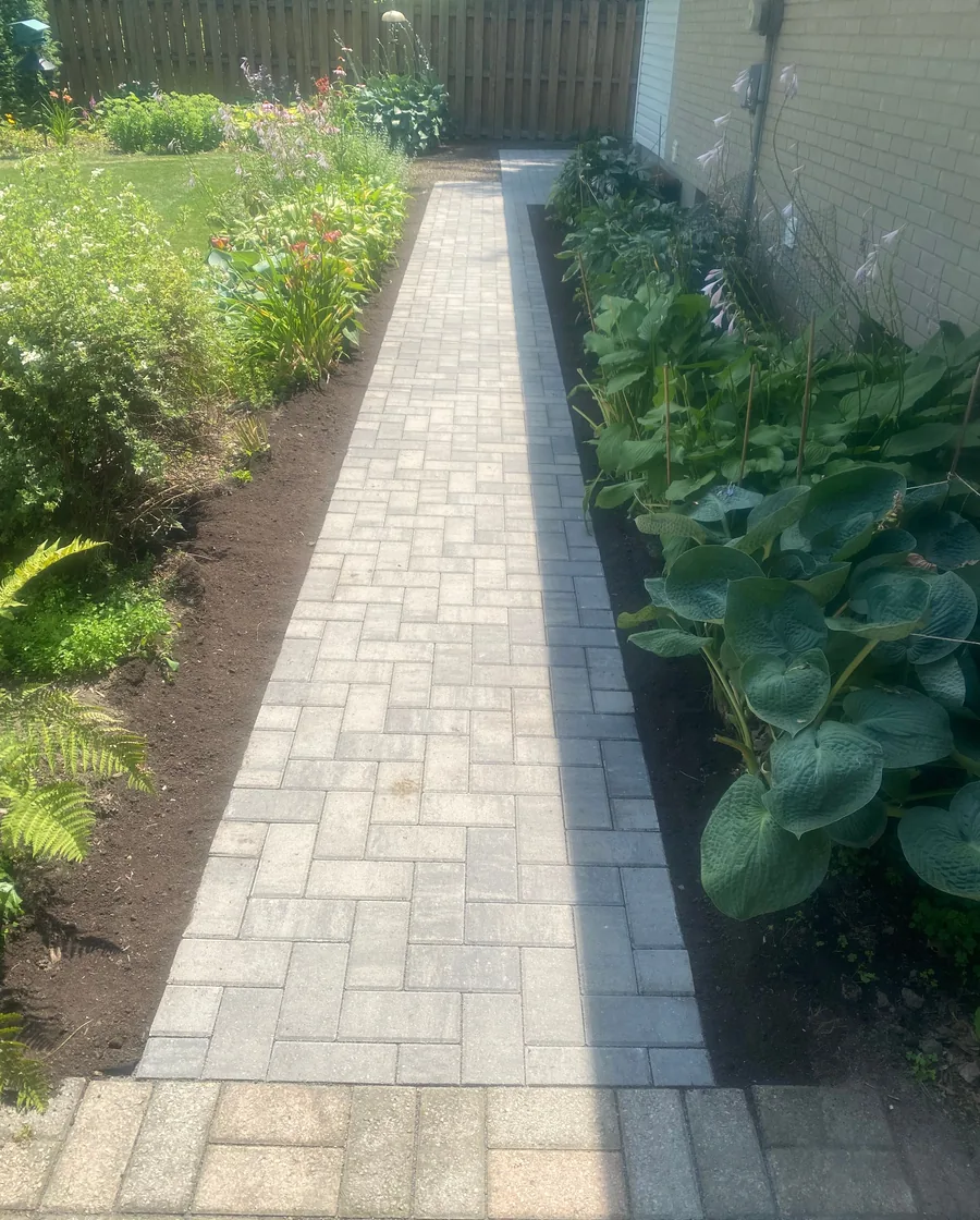 Paver walkway bordered by planted garden beds